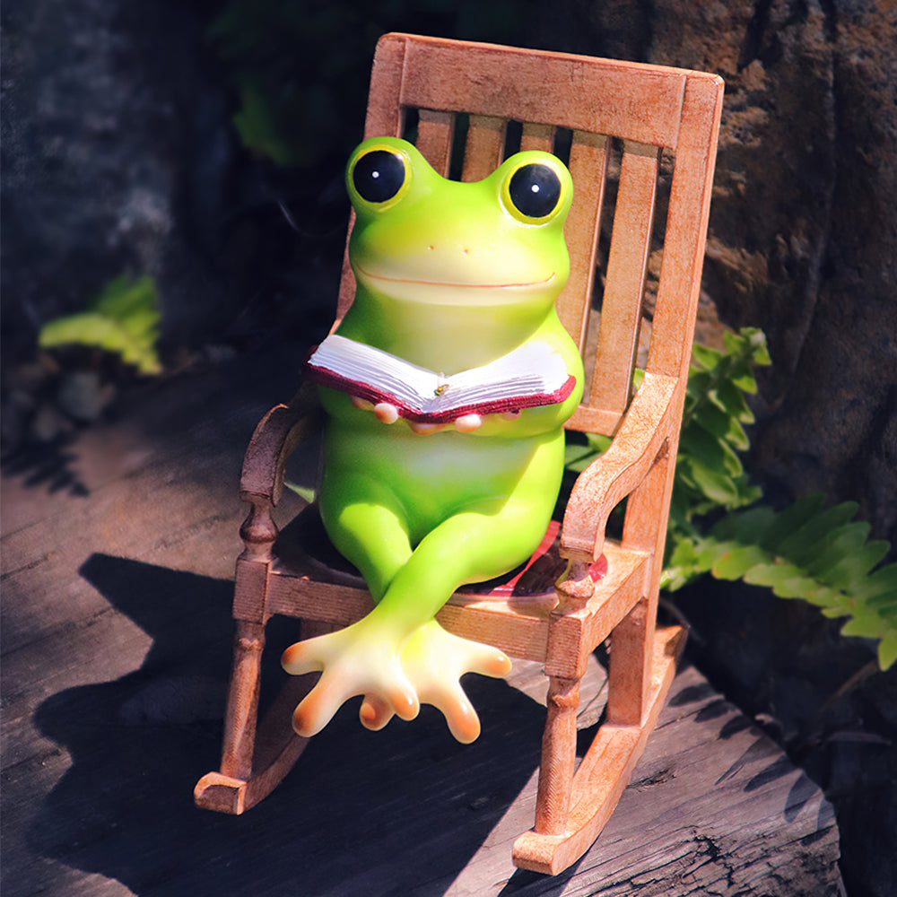 ロッキングチェアに座って本を読むカエルの置物