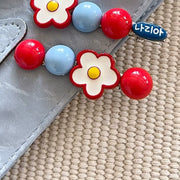 Daisy flower hair clips pair displayed on a silver bag with woven texture