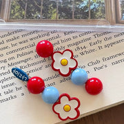 Red and blue beaded daisy hair clips styled on an open book page