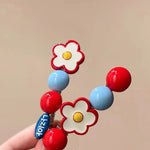 Two daisy flower beaded hair clips held in hand showing the pair set