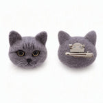 Two gray felt cat head hair clips shown on a white background, with one clip facing forward to show the face details and the other showing the silver metal claw fastener back.